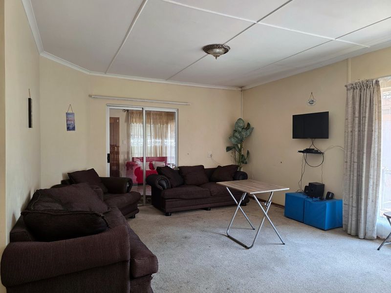 A living room featuring carpet flooring, ceiling tiles, and a sliding glass door providing access to an adjacent space.