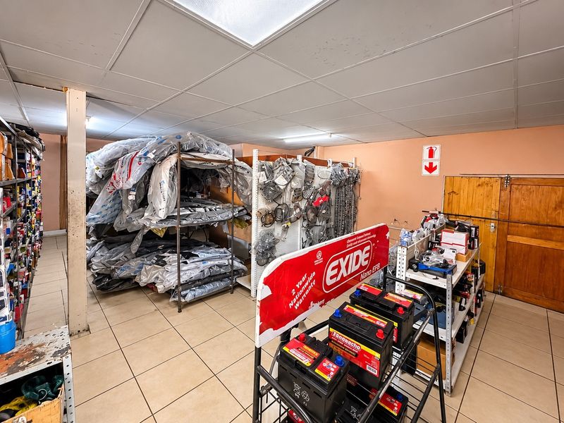 A functional commercial utility or storage space featuring tiled flooring, a suspended ceiling, and integrated shelving units for inventory management.