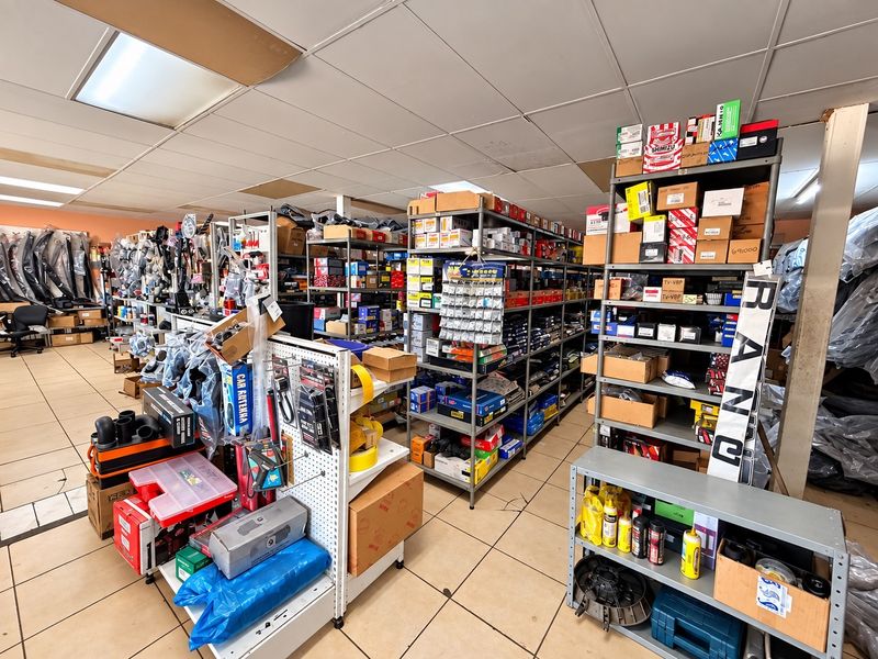 Commercial storage or retail space featuring industrial metal shelving units, suspended ceiling grid, and tiled flooring throughout.