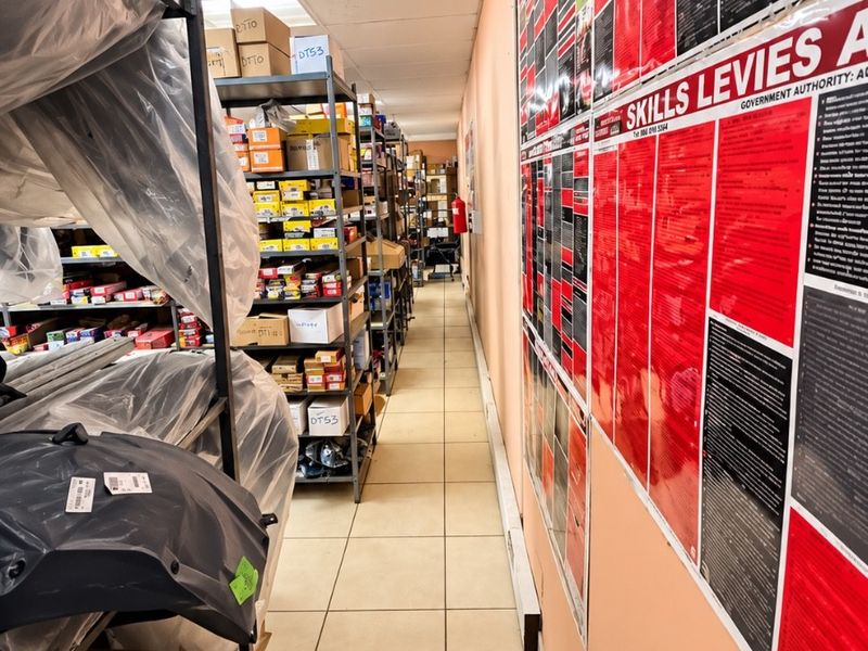 A narrow utility or storage corridor featuring tiled flooring, a suspended ceiling, and wall-mounted fire safety equipment.