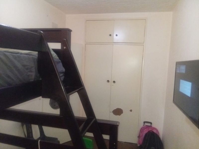 A compact bedroom featuring a built-in wardrobe with visible surface damage on the door panel.