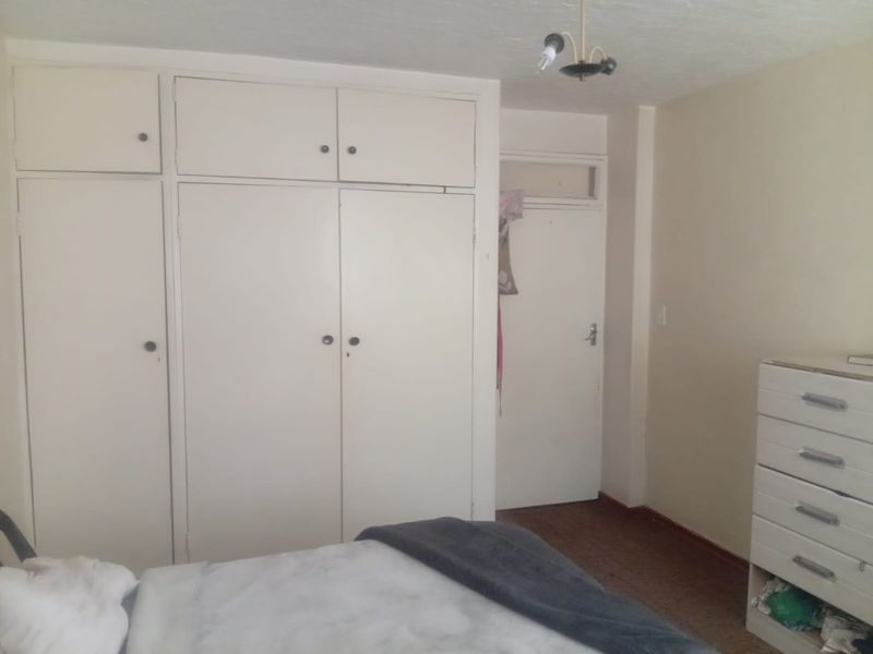 A bedroom featuring built-in storage cupboards and a standard internal door, requiring cosmetic updates to improve the overall aesthetic and condition.
