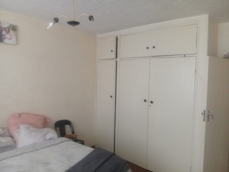 A bedroom featuring built-in cupboards with overhead storage units and a central ceiling light fixture.