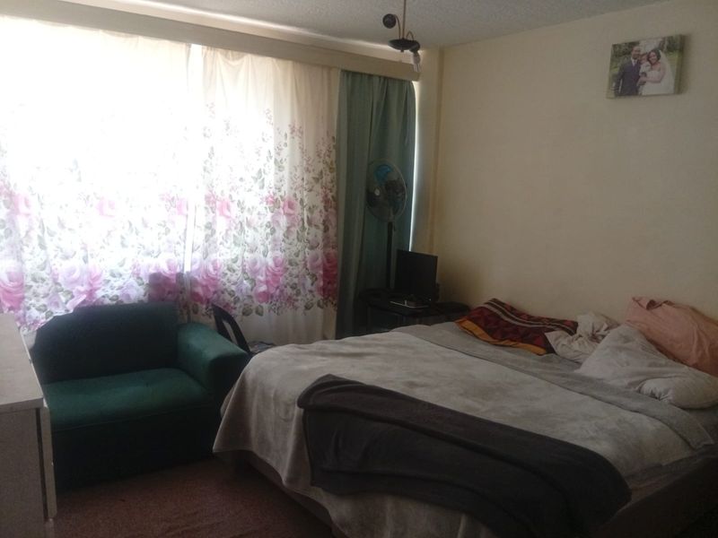 A bedroom featuring a large window with curtains and a central ceiling light fixture.