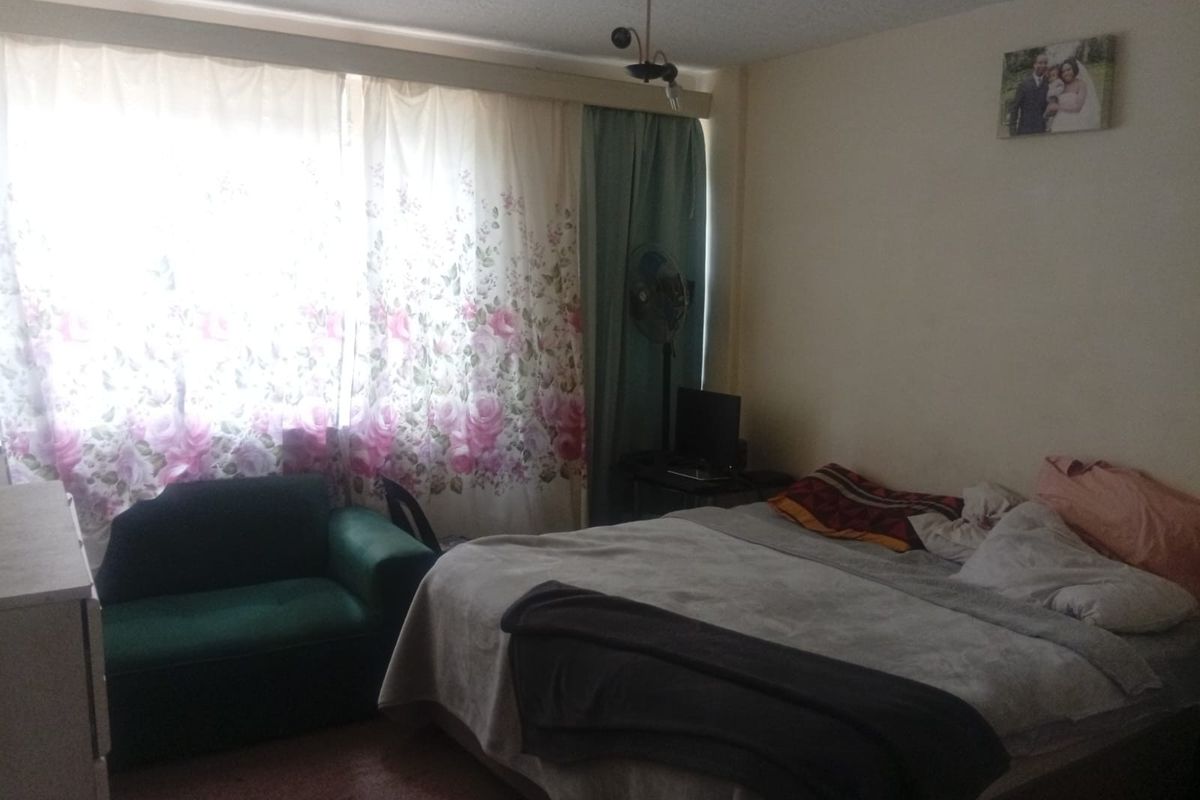 A bedroom featuring a large window with curtains and a central ceiling light fixture.
