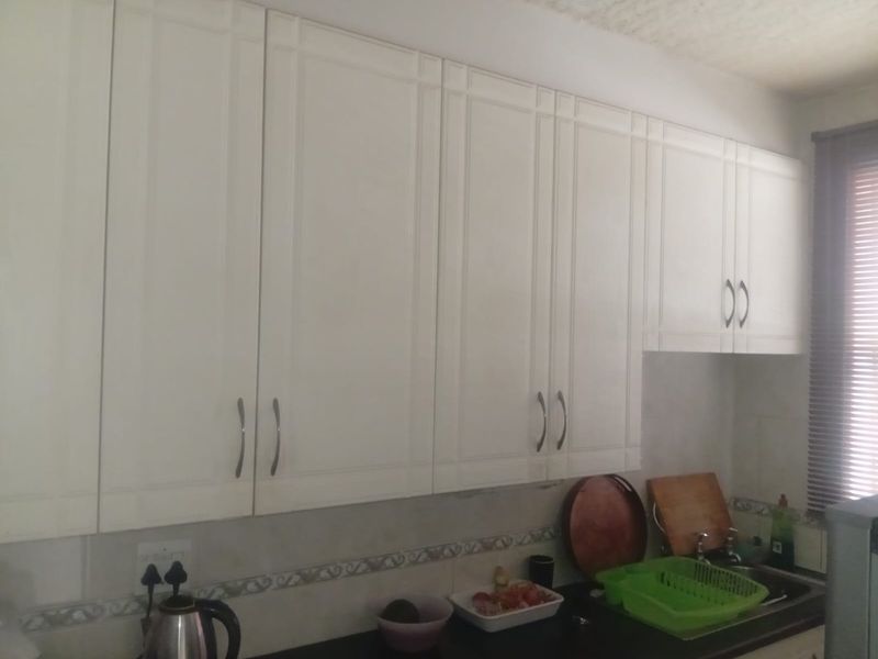 A functional kitchen area featuring white built-in cabinetry, a tiled backsplash, and a sink with faucet fixtures.