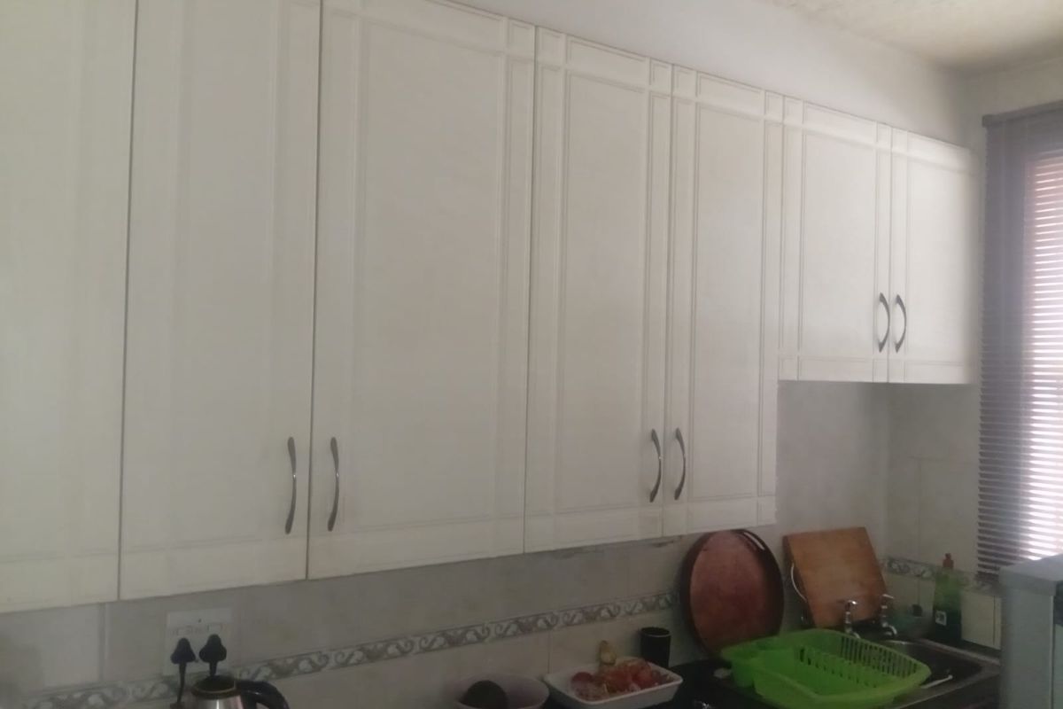 A functional kitchen area featuring white built-in cabinetry, a tiled backsplash, and a sink with faucet fixtures.