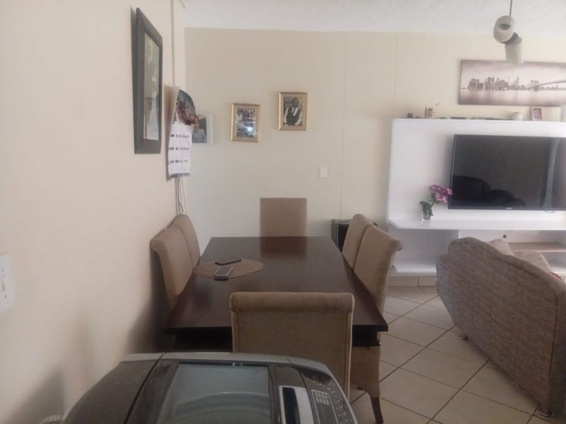Open plan living and dining area featuring tiled flooring and a built-in media unit, providing a functional space for relaxation and dining.