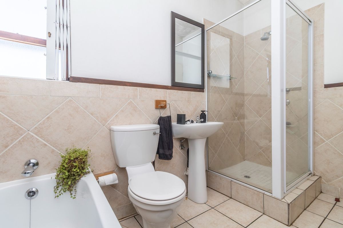 A functional bathroom featuring a pedestal basin, a separate shower enclosure, and a built-in bathtub with neutral ceramic wall and floor tiling.