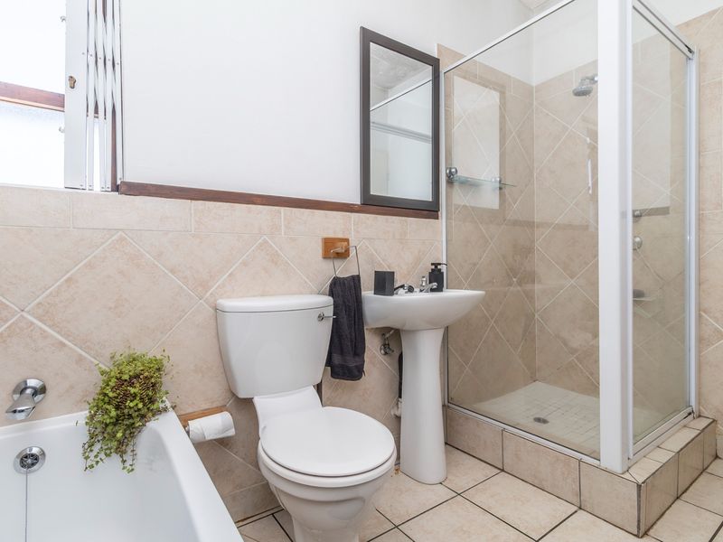 A functional bathroom featuring a pedestal basin, a separate shower enclosure, and a built-in bathtub with neutral ceramic wall and floor tiling.