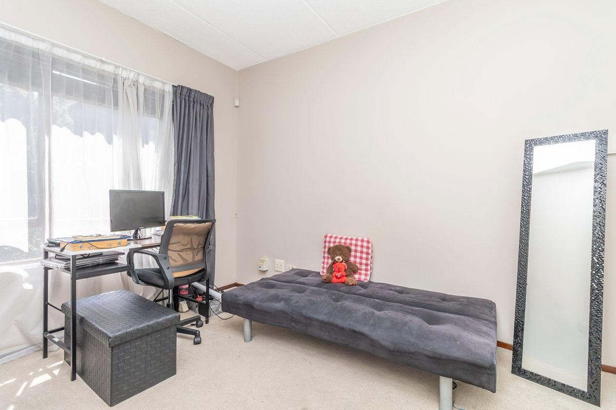 A functional bedroom space featuring neutral wall finishes, carpeted flooring, and large window access with installed curtain tracks.