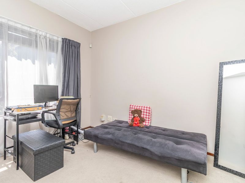 A functional bedroom space featuring neutral wall finishes, carpeted flooring, and large window access with installed curtain tracks.