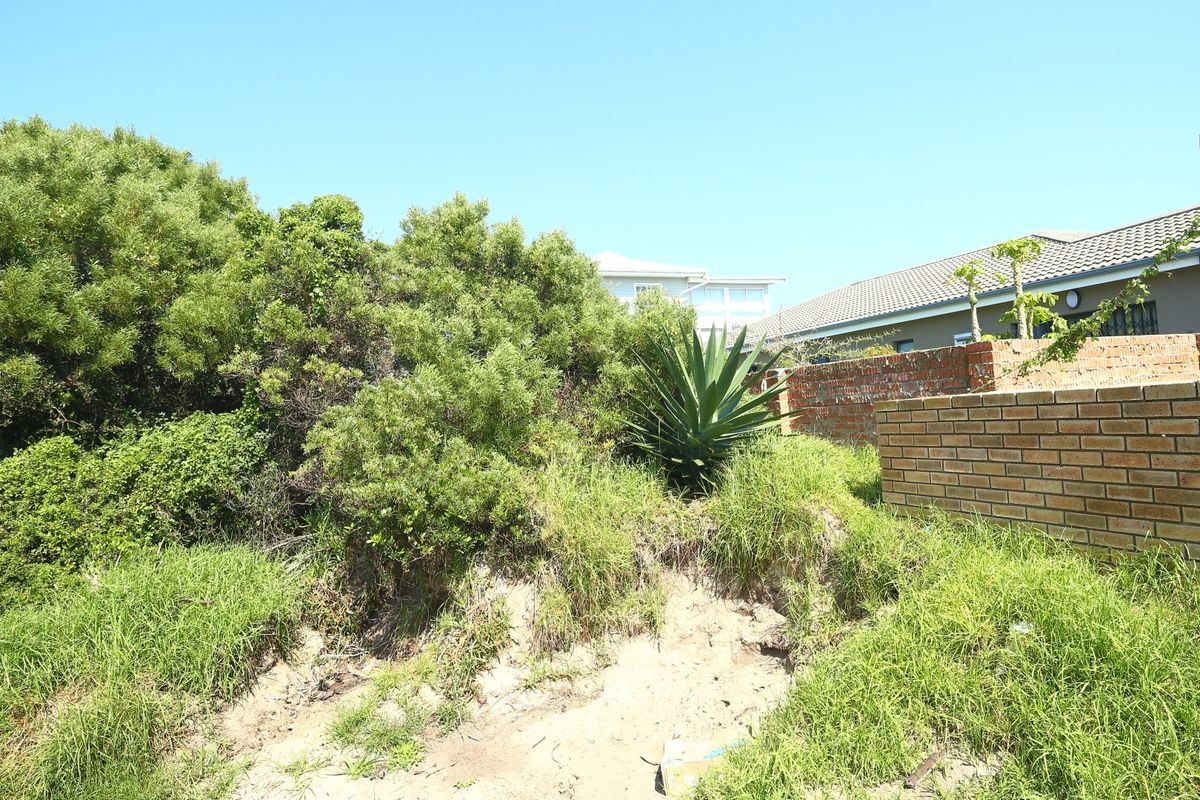 A view of the rear section of the residential vacant land, featuring a brick boundary wall and a timber pergola structure.