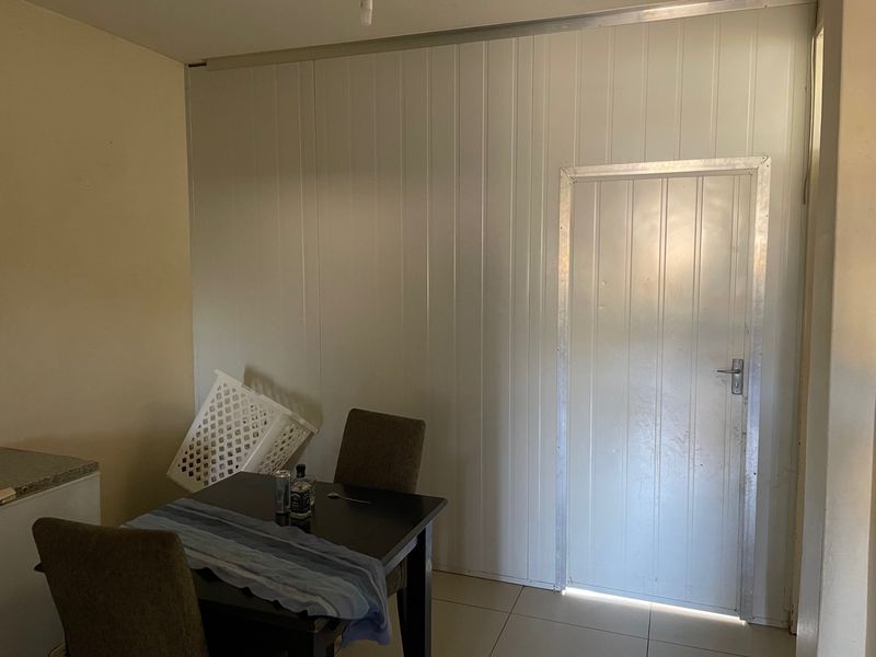 A living area featuring tiled flooring and a partition wall with an integrated door, showing signs of dated finishes.
