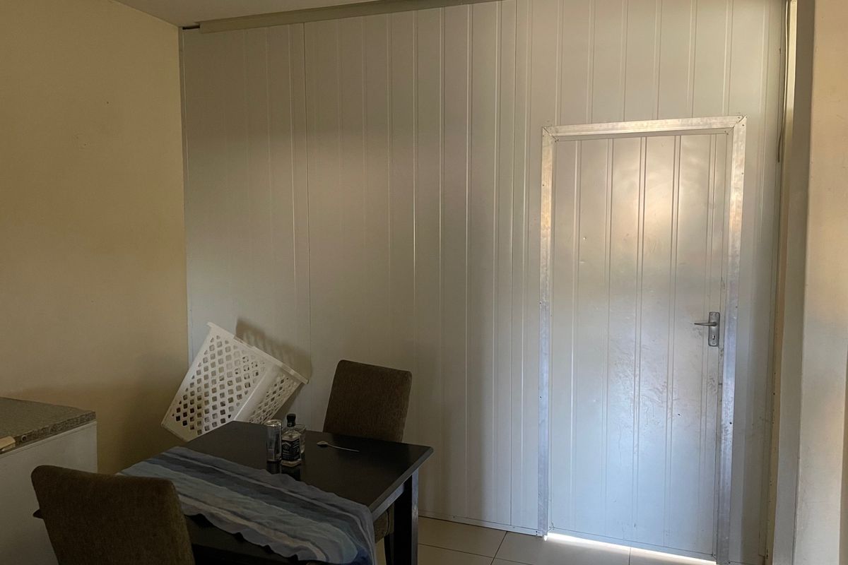 A living area featuring tiled flooring and a partition wall with an integrated door, showing signs of dated finishes.