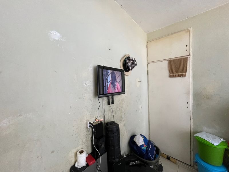 A bedroom interior featuring a built-in cupboard, currently showing significant wall surface wear and finish deterioration requiring maintenance.