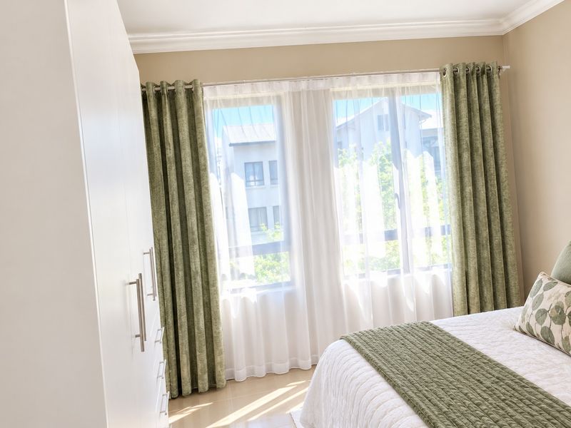 A bright and well-maintained bedroom featuring a built-in wardrobe, tiled flooring, and decorative ceiling cornicing, offering a clean and comfortable living space.