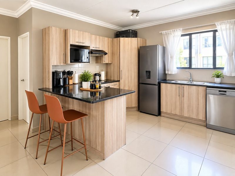 Modern kitchen featuring light wood-grain cabinetry, black granite countertops, a breakfast bar, and tiled flooring, offering a clean and functional culinary space.