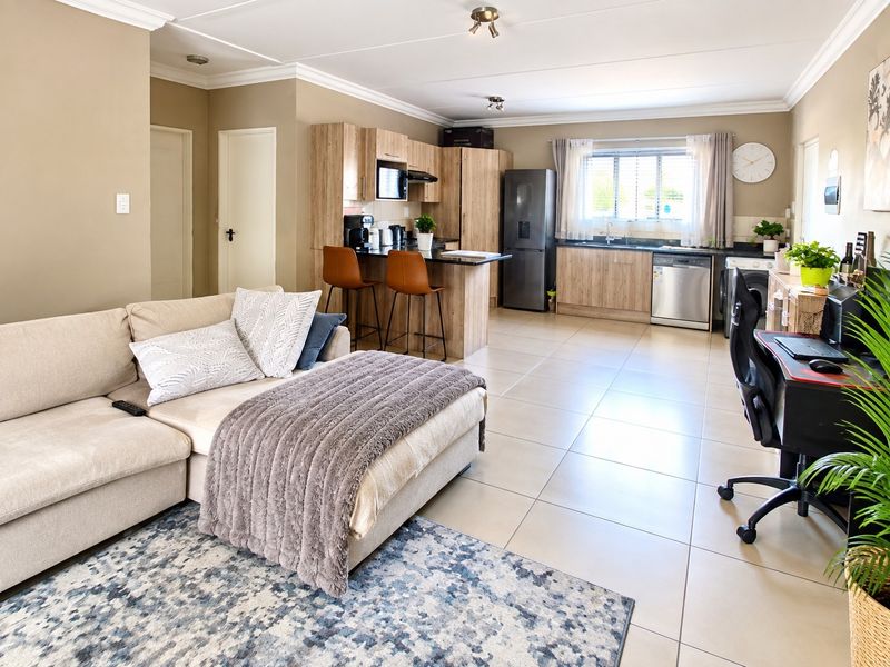 Spacious open-plan living area featuring a modern kitchen with wood-finish cabinetry, a central island, and tiled flooring throughout.