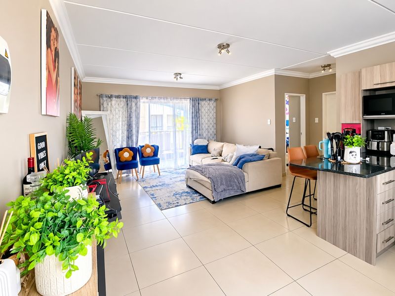 An open-plan living and kitchen area featuring tiled floors, a modern kitchen island with built-in cabinetry, and a sliding door leading to the balcony.
