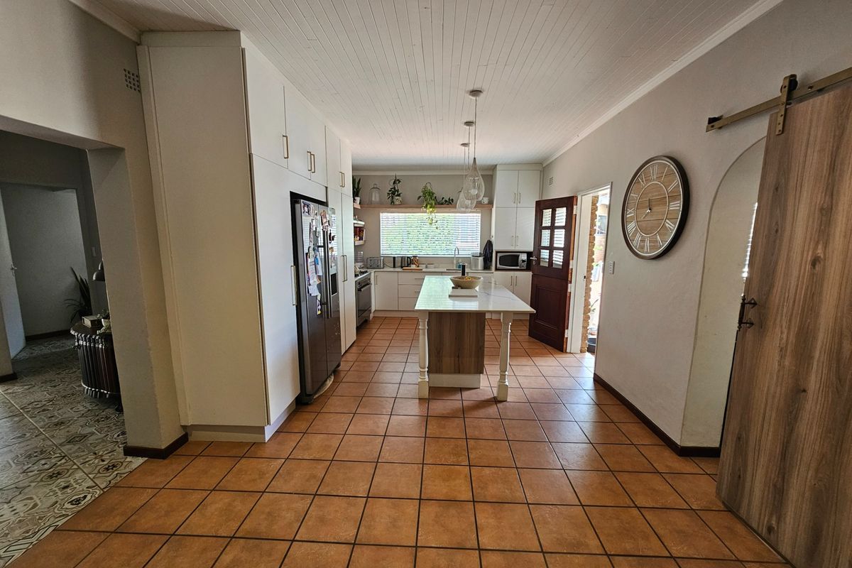 Spacious kitchen featuring a central island, ample built-in cabinetry, tiled flooring, and a distinctive tongue and groove ceiling with a sliding barn door entrance.