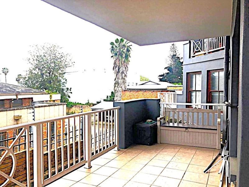 A spacious covered balcony featuring tiled flooring and a metal balustrade, offering an open outdoor area suitable for relaxation.