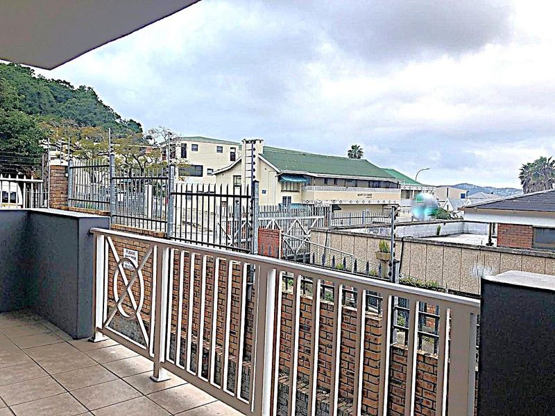 A covered balcony area featuring tiled flooring and metal balustrades, offering an elevated view of the surrounding commercial property and neighbourhood.
