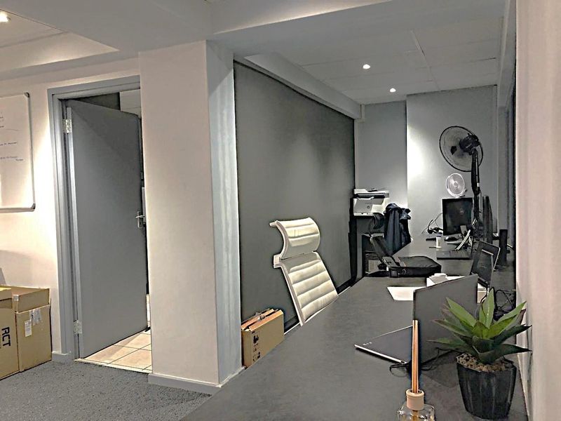 A functional commercial office space featuring a built-in desk, recessed ceiling lighting, and a neutral color palette suitable for a professional work environment.