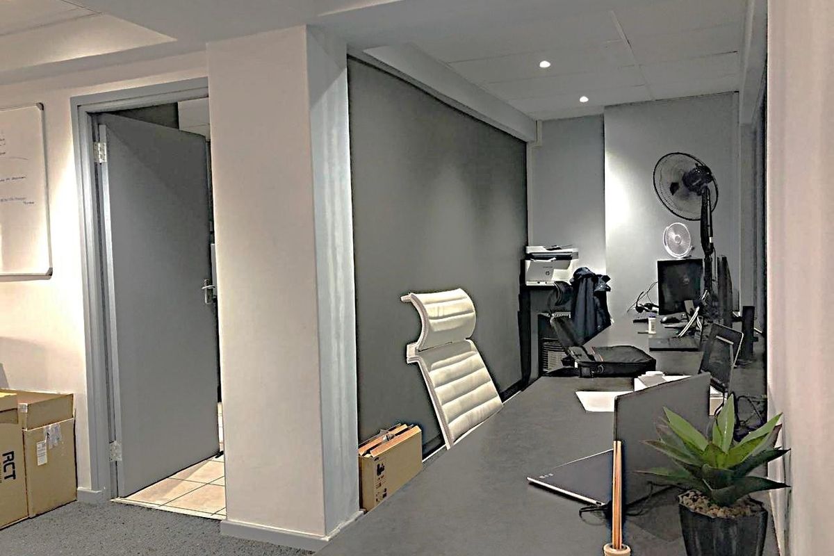 A functional commercial office space featuring a built-in desk, recessed ceiling lighting, and a neutral color palette suitable for a professional work environment.
