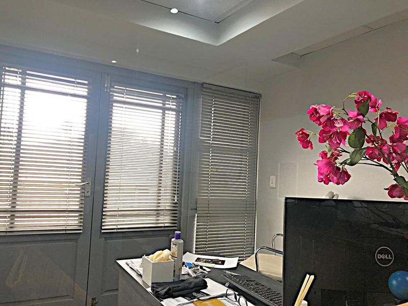 A professional office space featuring recessed ceiling lighting and large glass doors fitted with venetian blinds for adjustable natural light.