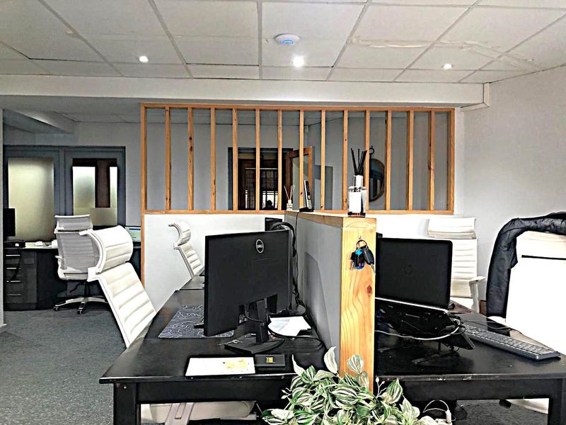 A functional commercial office space featuring a timber partition screen, suspended ceiling with recessed lighting, and carpeted flooring.