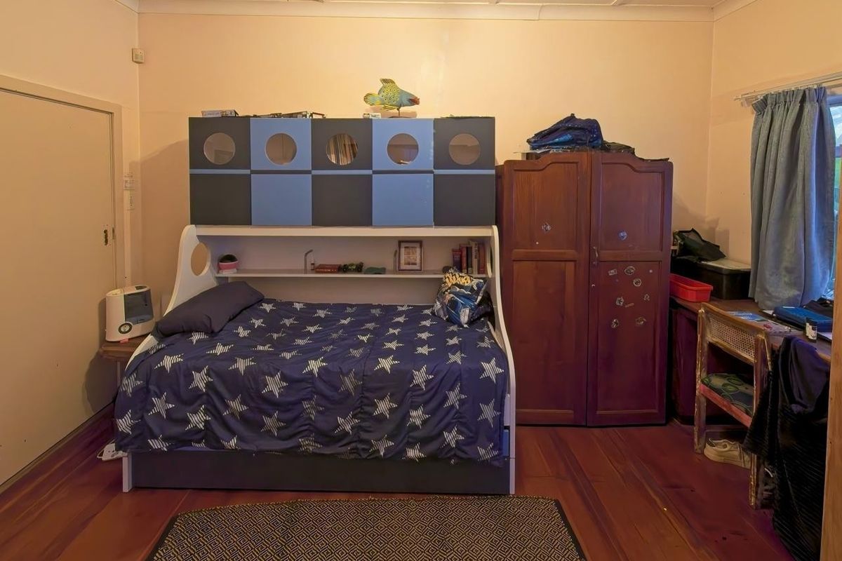 A bedroom featuring original timber flooring and a panelled ceiling, requiring cosmetic updates to improve the overall finish and appeal.
