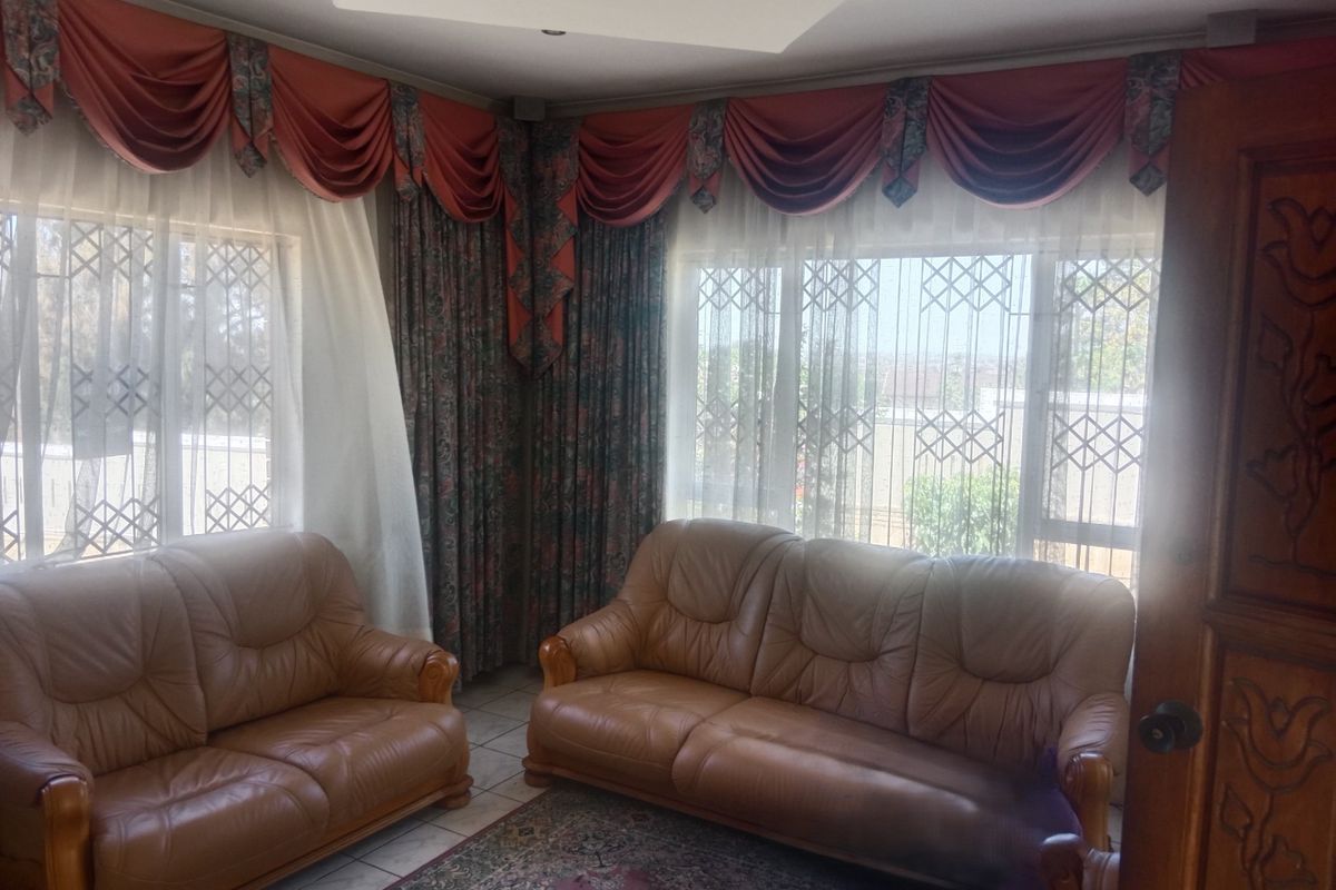 A living room featuring tiled flooring, recessed ceiling lighting, and security gates on the windows.