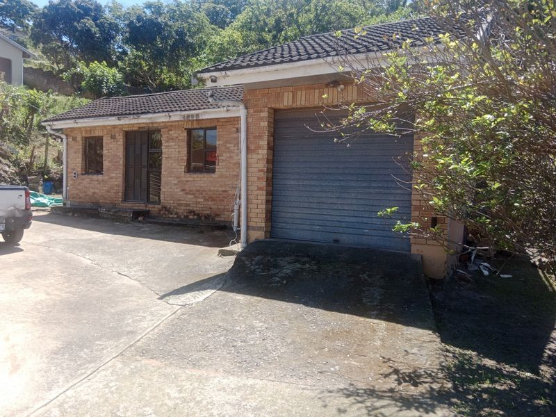 Front exterior view of a face brick house featuring a single roller shutter garage door and a concrete driveway.
