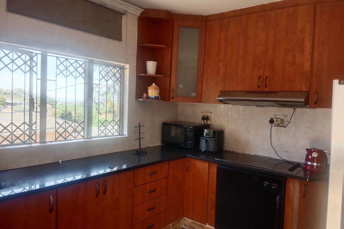 A functional kitchen featuring wooden cabinetry, granite countertops, and integrated appliances, offering a practical layout with natural light and security features.