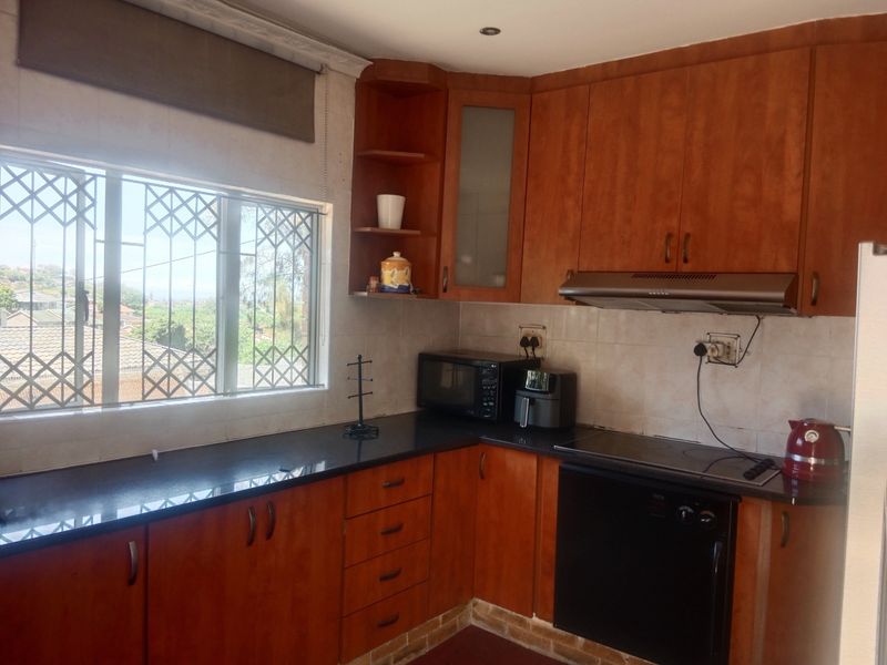 A functional kitchen featuring wooden cabinetry, granite countertops, and integrated appliances, offering a practical layout with natural light and security features.