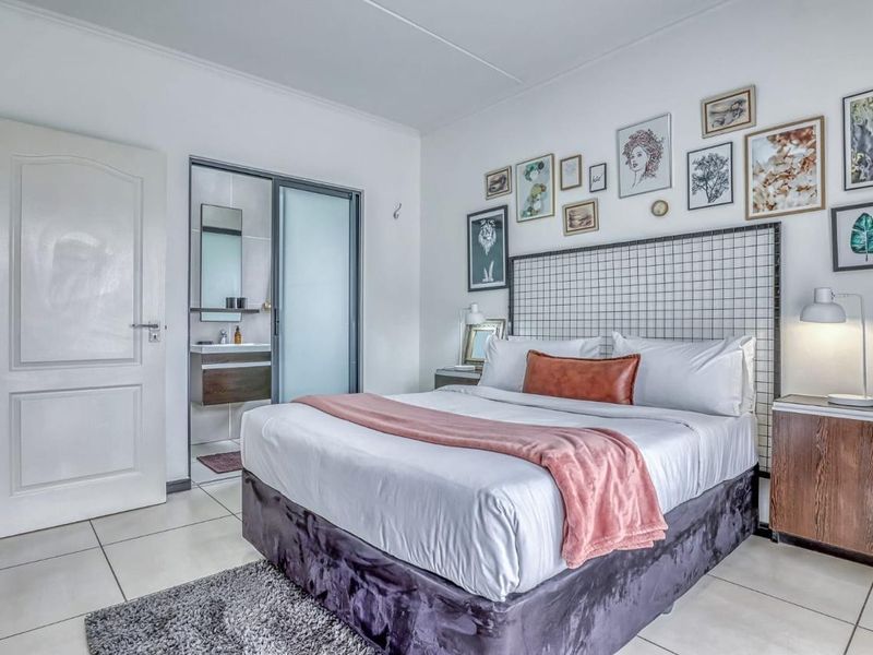 A well-maintained bedroom featuring tiled flooring and an integrated en-suite bathroom with a modern vanity unit.