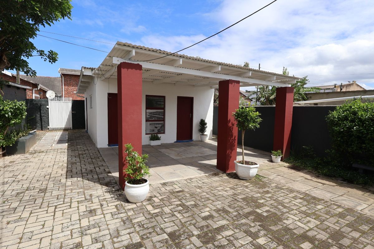 Rear exterior view of the office property featuring a paved driveway, covered patio area with brick pillars, and secure boundary walling.