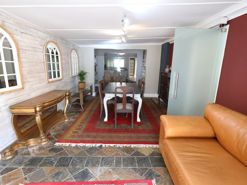 Open plan office or dining area featuring stone tile flooring, decorative wall paneling, and a modern frosted glass sliding door.