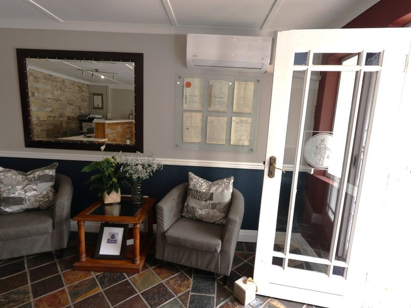 Welcoming office entrance area featuring slate tile flooring, wainscoting, and a glass-panelled door, equipped with a wall-mounted air conditioning unit.
