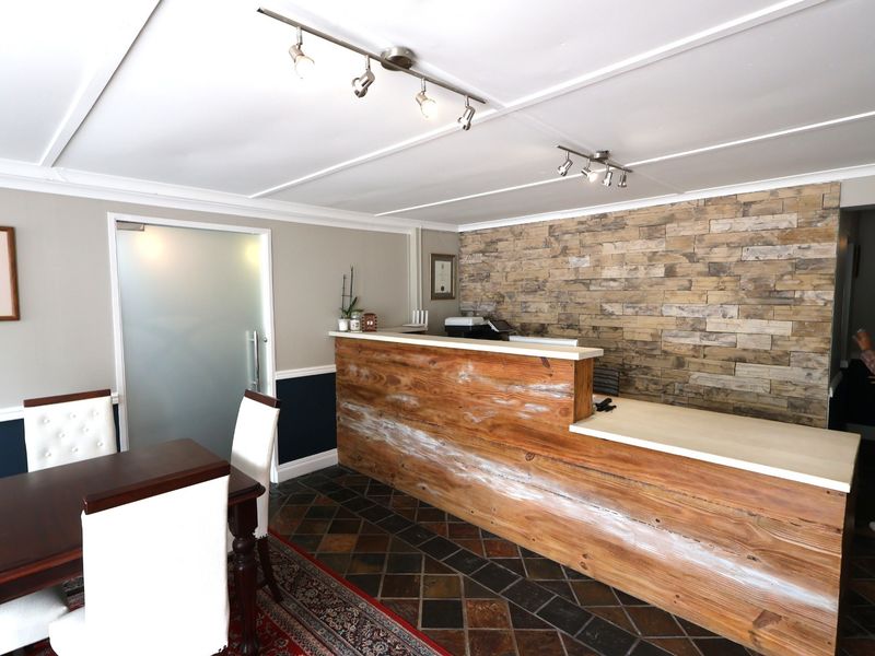Office reception area featuring a rustic wood-fronted desk, stone veneer accent wall, frosted glass door, and tiled flooring with overhead track lighting.