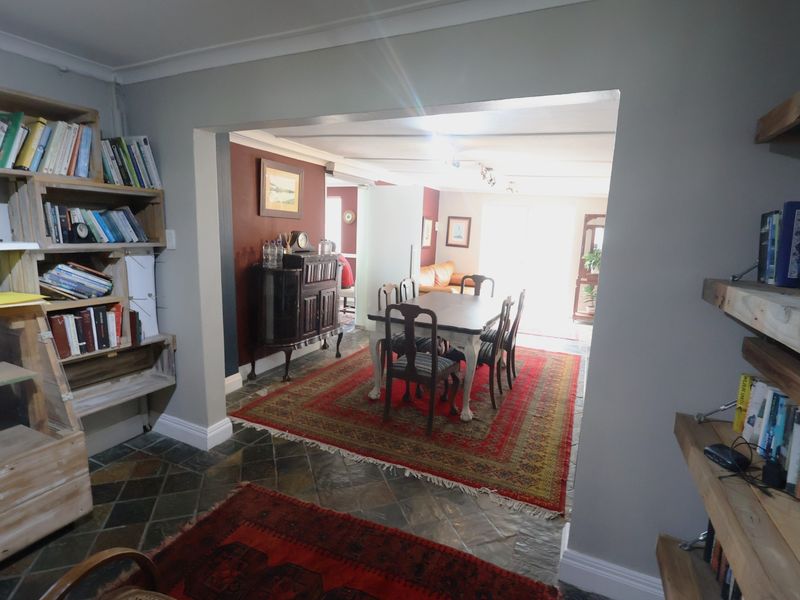 Open plan living and dining area featuring stone tile flooring, built-in shelving units, and a spacious layout connecting the two zones.