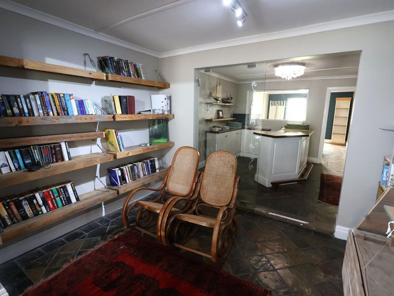 Office space featuring built-in wooden shelving, stone tile flooring, and a glass partition wall leading to an adjacent room.