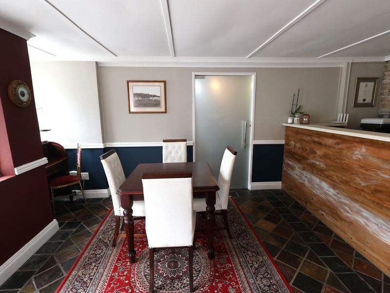 A professional office space featuring a reception counter, stone tile flooring, wainscoting, and a frosted glass door.