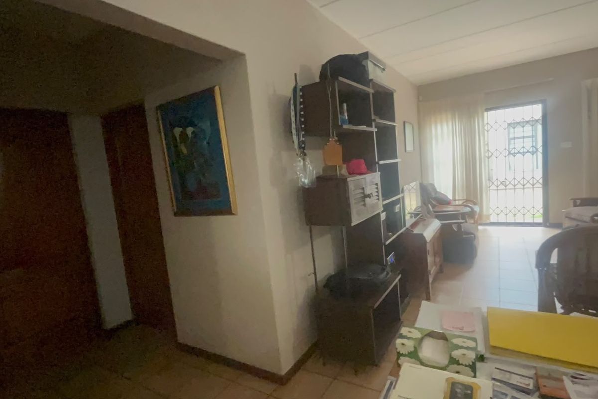 A living area featuring tiled flooring and a sliding glass door with a security gate, providing access to the exterior.