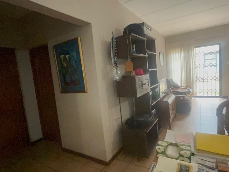 A living area featuring tiled flooring and a sliding glass door with a security gate, providing access to the exterior.