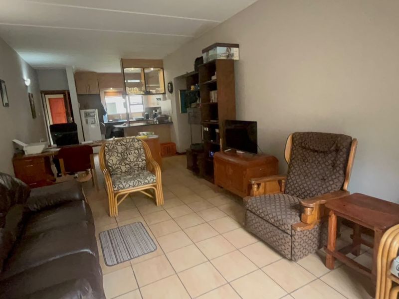 An open-plan living area featuring tiled flooring and a connected kitchen space with built-in cabinetry and a breakfast counter.