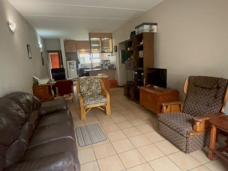 Open-plan living area featuring ceramic floor tiles and a connected kitchen space, offering a functional layout for daily living.