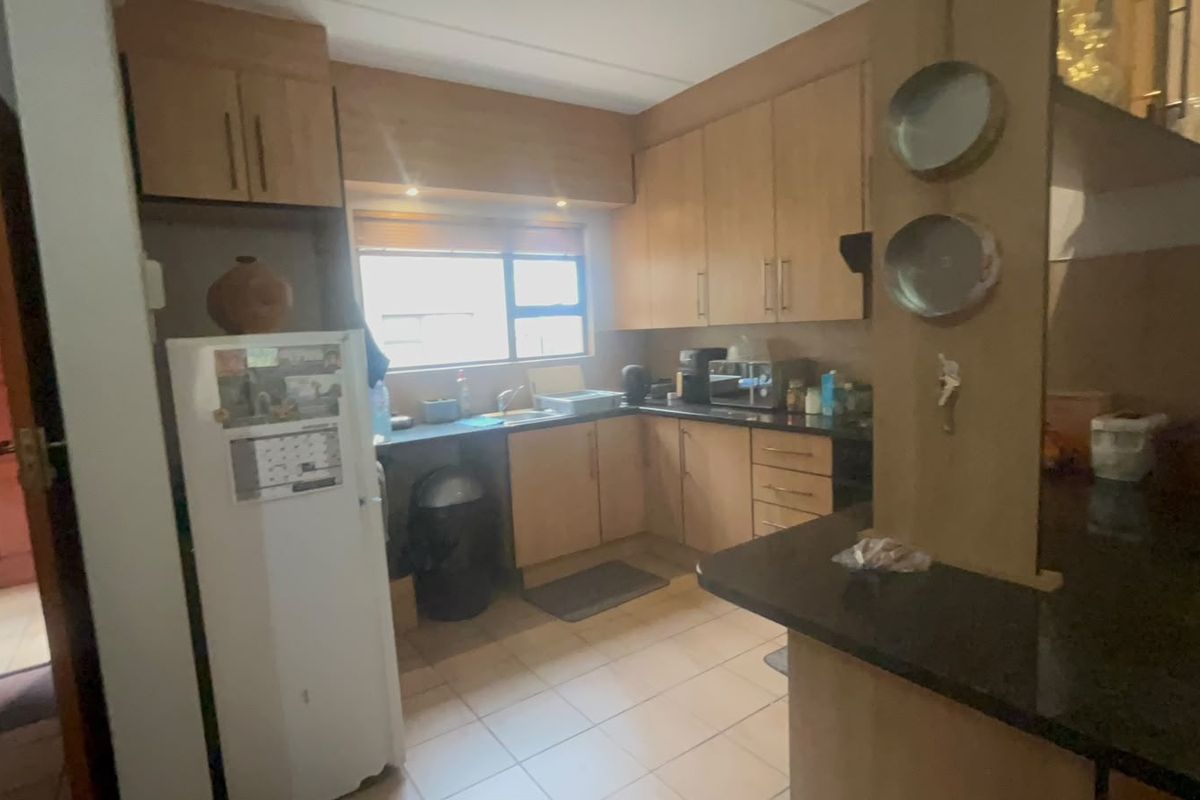 A functional kitchen featuring built-in wooden cabinetry, laminate countertops, a breakfast bar, and tiled flooring, offering a practical layout for daily use.
