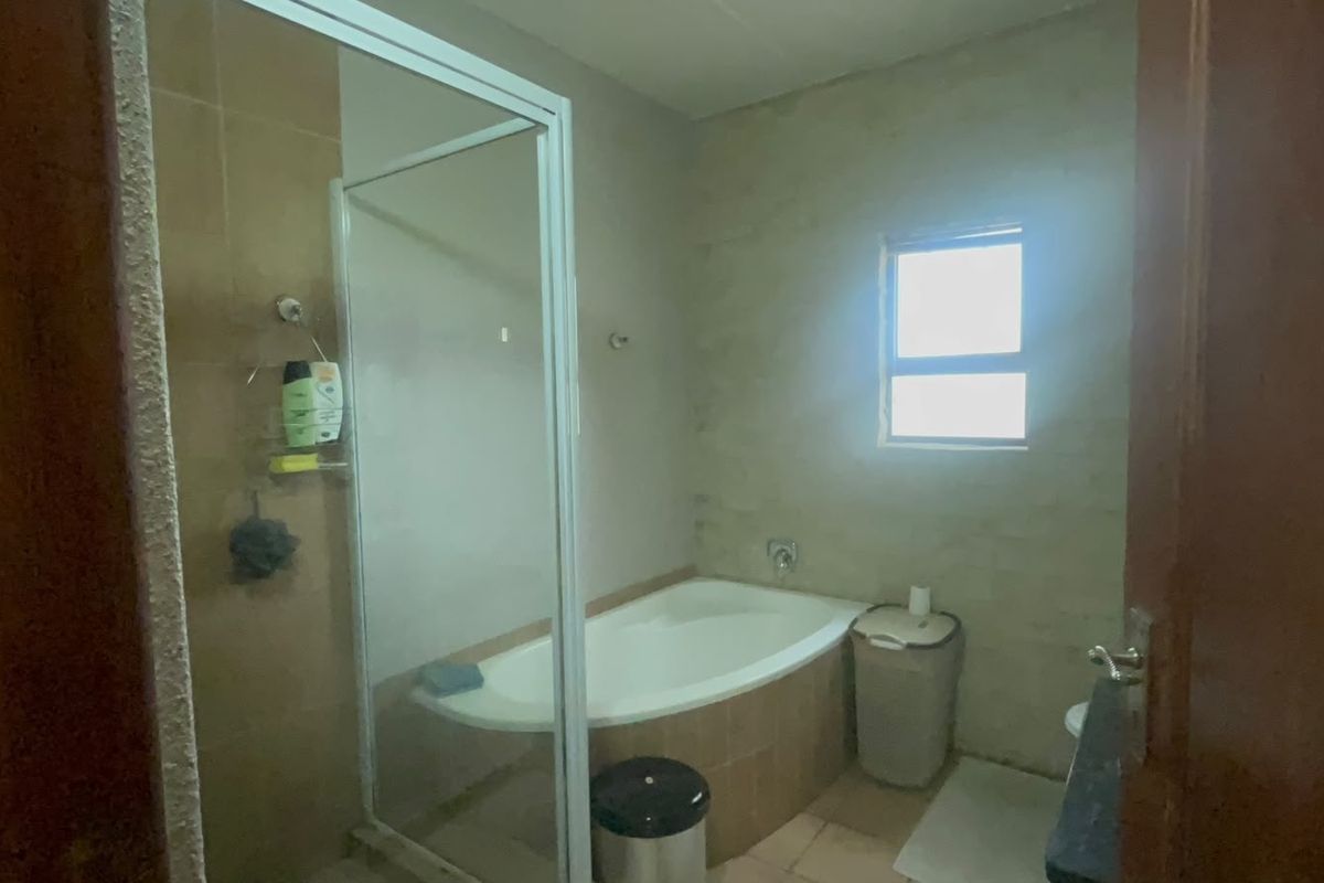A functional bathroom featuring a built-in bathtub, a separate shower enclosure, and tiled finishes, offering a practical layout ready for modern updates.